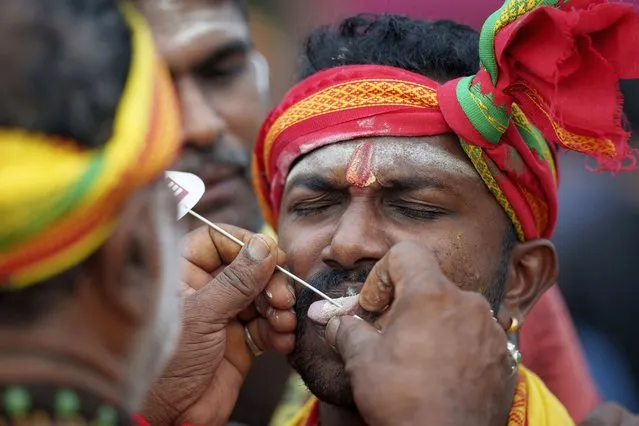 A Hindu devotee gets his tongue pierced with a metal rod during the Thaipusam festival celebrations at Batu Caves, in Kuala Lumpur, Malaysia, Sunday, February 5, 2023. Thaipusam, which is celebrated in honor of Hindu god Lord Murugan, is an annual procession by Hindu devotees seeking blessings, fulfilling vows and offering thanks. (Photo by Vincent Thian/AP Photo)
