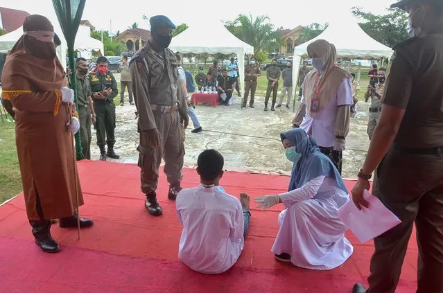 A man (lower C) collapses in pain while getting publicly flogged by a member of the Sharia police after he was found guilty of raping a child, in Idi Rayeuk, East Aceh on November 26, 2020. (Photo by Cekmad/AFP Photo)