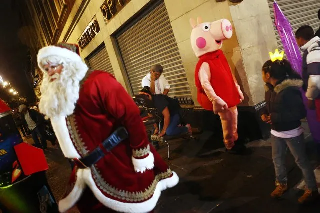 People dressed as Santa Claus and children's character Chanchita Pepa walk on a street, as a man gives a massage to a woman in Mexico City December 23, 2014. (Photo by Edgard Garrido/Reuters)