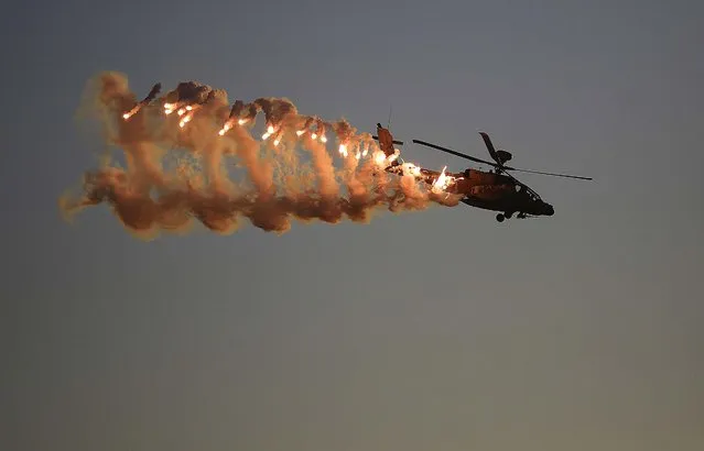 An Israeli Air Force Apache helicopter releases flares during a graduation ceremony for new pilots in the Hatzerim air force base near the city of Beersheba, southern Israel, Thursday, December 25, 2014. (Photo by Tsafrir Abayov/AP Photo)