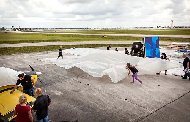 Painting is halted so more plastic tarp can be laid on the tarmac. A small private plane near the painting area was  speckled in blue paint and had to be cleaned before the princess could continue with the multiple canvases planned for the day. (Photo by Thomas Cordy/The Palm Beach Post)