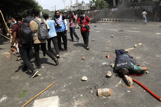 An injured policeman lies on a street during clashes with students during dayslong protests over the allocation of government jobs, in Dhaka, Bangladesh, July 18, 2024. (Photo by Rajib Dhar/AP Photo)
