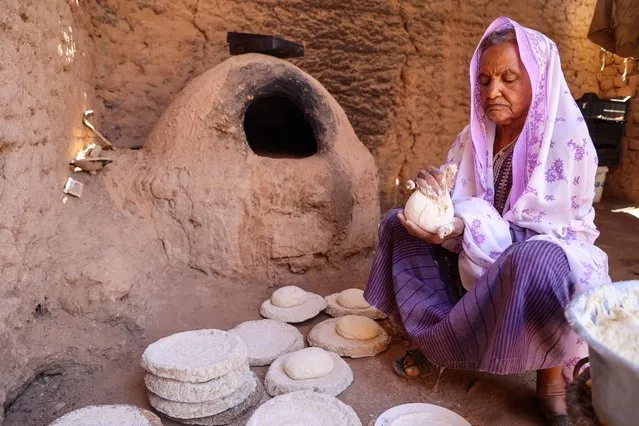 Local resident Naamat Jabal Sayyid Hasan, 75, bakes bread in a mud hut as she does daily to offer to people fleeing war-torn Sudan passing through in the northern town of Wadi Halfa near the border with Egypt, on April 29, 2023. Tens of thousands of people have been uprooted within Sudan or embarked on arduous trips to neighbouring Chad, Egypt, South Sudan and Ethiopia to flee as fierce fighting between Sudan's army and paramilitaries entered a third week, violating a renewed truce. (Photo by Ashraf Shazly/AFP Photo)