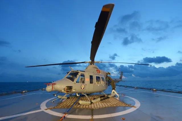 Indonesian navy personnel check a helicopter as they prepare operations to lift the tail of AirAsia Flight 8501 in Java sea, Indonesia Friday, January 9, 2015. Days after sonar detected apparent wreckage, an unmanned underwater vehicle showed the plane's tail, lying upside down and partially buried in the ocean floor. (Photo by Adek Berry/AP Photo)