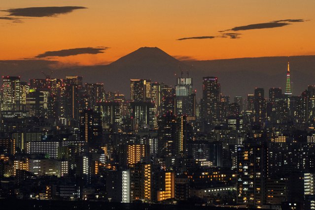 A general view shows Japan's highest mountain, Mt. Fuji (3,776m or 12,388 feet) and skyscrapers in central Tokyo at sunset on November 17, 2025. Japan's economy shrank 0.4 percent in the three months to September, official data showed on November 17, as new Prime Minister Sanae Takaichi's government prepares a major stimulus package. (Photo by Kazuhiro Nogi/AFP Photo)