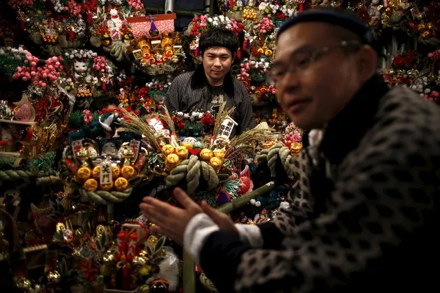 Men promote selling rakes, known as "kumade", decorated with imitation gold coins and other objects during the Tori-no-Ichi fair at Ohtori shrine in downtown Tokyo, Japan, November 29, 2015. The decorative "kumade" miniatures are sold, along with various other charms, to symbolise raking in fortune for the businesses, during this festival. The Tori-no-Ichi fair has been held twice or thrice every November since the Japanese Edo era. (Photo by Issei Kato/Reuters)