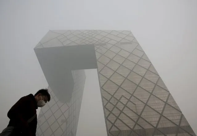 A man wearing a mask walks past the China Central Television (CCTV) building during a heavily polluted day in Beijing, November 30, 2015. (Photo by Kim Kyung-Hoon/Reuters)
