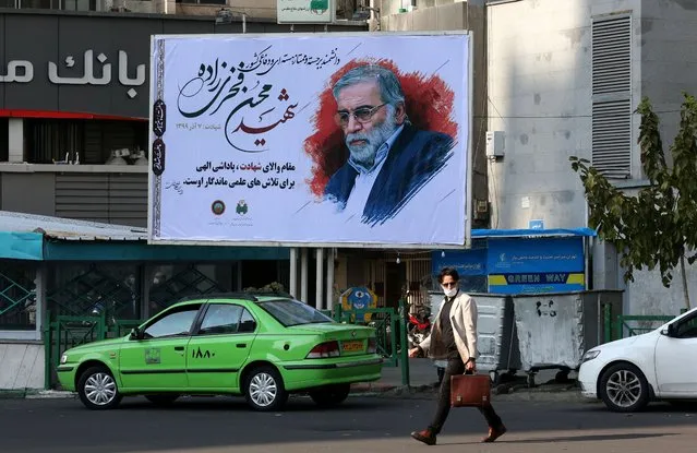 An Iranian man walks by a billboard of slain Iranian nuclear scientist Mohsen Fakhrizadeh in Tehran, on November 30, 2020. Iran laid to rest a nuclear scientist in a funeral befitting a top “martyr”, vowing to redouble his work after an assassination pinned on arch-foe Israel. Fakhrizadeh died on November 27 from his wounds after assailants targeted his car and engaged in a gunfight with his bodyguards outside the capital, according to the defence ministry, heightening tensions once more between Tehran and its foes. (Photo by Atta Kenare/AFP Photo)
