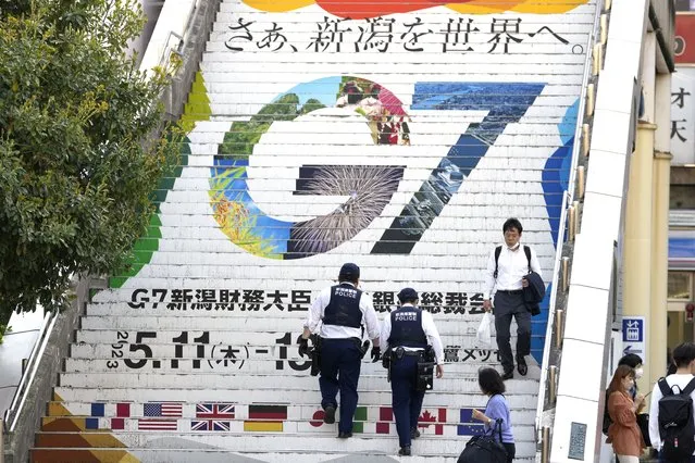 Police officers go up the station stairs depicting the logo of the G7 Finance Ministers and Central Bank Governors meeting, in Niigata, Japan, Wednesday, May 10, 2023. The G7 Niigata is scheduled on May 11-13. (Photo by Shuji Kajiyama/AP Photo)
