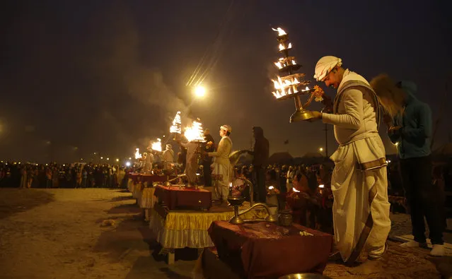 Hindu priests perform evening rituals at the Sangam, the confluence of the Rivers Ganges, Yamuna and mythical Saraswati, during the annual Magh Mela traditional fair in Allahabad, India, Saturday, January 17, 2015. (Photo by Rajesh Kumar Singh/AP Photo)