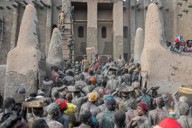 People carry buckets of mud used to re-plaster the Great Mosque of Djenne in central Mali on June 4, 2023. (Photo by Ousmane Makaveli/AFP Photo)