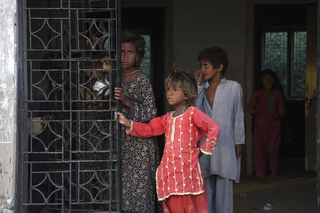 Children look out as they take shelter with their families in a school building after fleeing from their villages due to Cyclone Biparjoy approaching, at a costal area of Badin district, in Pakistan's Sindh province, Tuesday, June 13, 2023. (Photo by Umair Rajput/AP Photo)