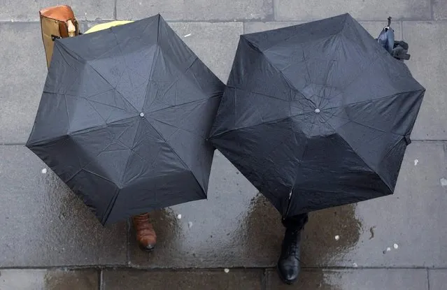 People shelter under umbrellas as they walk through central London January 31, 2015. (Photo by Neil Hall/Reuters)