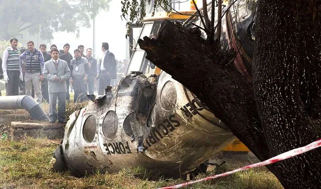 Indian investigators look at the remains of a small Indian paramilitary plane that crashed outside the airport in New Delhi, India, Tuesday, December 22, 2015. An inquiry has been ordered to determine that cause of the crash of the Super King plane belonging to India's Border Security Force, Junior Aviation Minister Mahesh Sharma told reporters. (Photo by Manish Swarup/AP Photo)