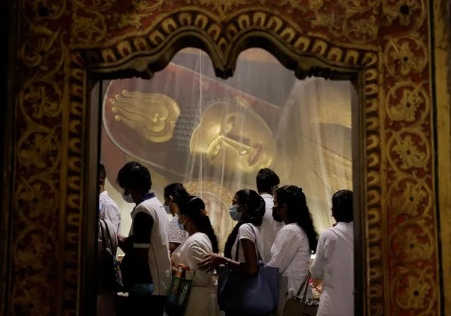Devotees walk past a statue of Buddha as they worship on Vesak day to commemorate the birth, enlightenment and death of Buddha, at Kelaniya Buddhist temple, in Colombo, Sri Lanka on May 5, 2023. (Photo by Dinuka Liyanawatte/Reuters)