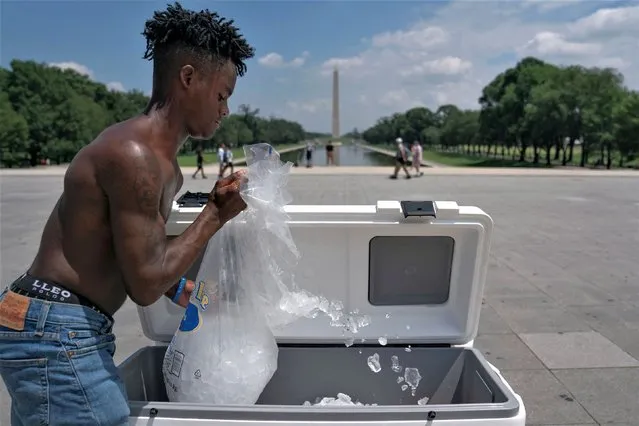 Water vendor Jayden Harris dumps ice into a cooler near the Lincoln Memorial during high temperatures, in Washington, U.S., July 19, 2023. (Photo by Nathan Howard/Reuters)