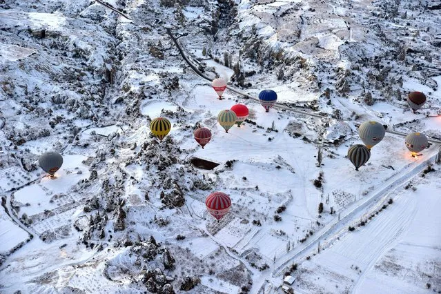 Hot air balloons fly over the famous volcanic rock formations during the winter season in Cappadocia, a historical region in central Anatolia in Nevsehir, Turkey, January 3, 2016. (Photo by Anadolu Agency/Getty Images)