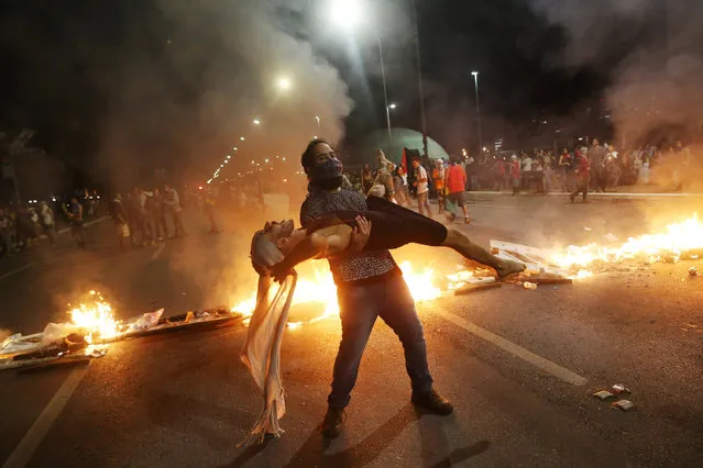 Anti-government demonstrators perform in front of burning barricades as they attend a protest against a constitutional amendment, known as PEC 55, that limit public spending, in front of Brazil's National Congress in Brasilia, Brazil, November 29, 2016. (Photo by Adriano Machado/Reuters)