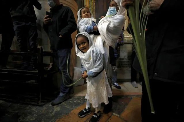 Christian worshippers hold palm fronds during a Palm Sunday procession in the Church of the Holy Sepulchre in Jerusalem's Old City on March 28, 2021. (Photo by Ammar Awad/Reuters)