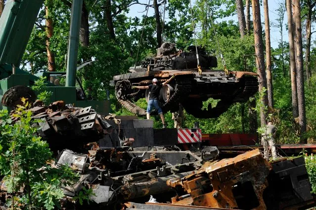 Ukrainian servicemen collect destroyed Russian tanks outside the village of Dmytrivka, in Kyiv region, on June 20, 2022 amid the Russian invasion of Ukraine. (Photo by Sergei Chuzavkov/AFP Photo)