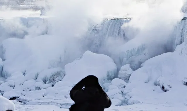 A man photographs ice masses formed around the American Falls as seen from Niagara Falls, Ontario, Canada, Thursday, February 19, 2015. (Photo by Aaron Lynett/AP Photo/The Canadian Press)