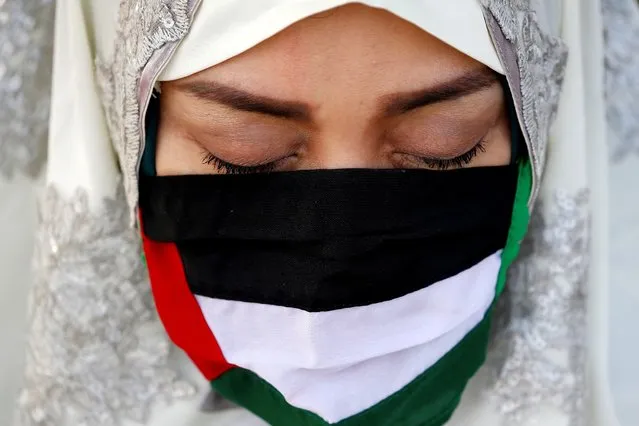 An Indonesian Muslim wears a face mask, designed in the likeness of the Palestinian flag, to curb the spread of the coronavirus disease (COVID-19) as she prays at the Great Mosque of Al Azhar during Eid al-Fitr, marking the end of the holy fasting month of Ramadan, in Jakarta, Indonesia, May 13, 2021. (Photo by Willy Kurniawan/Reuters)