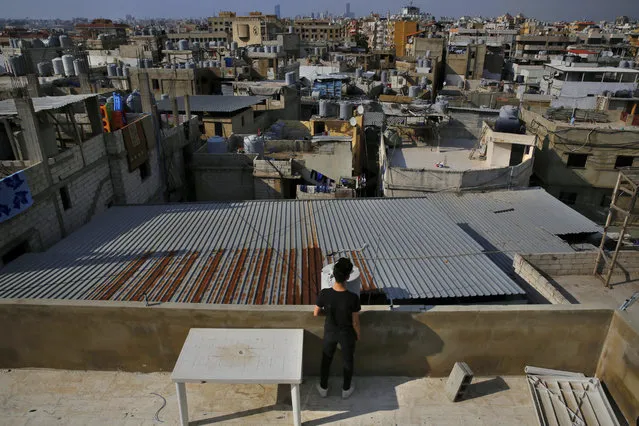 In this Thursday, May 4, 2017 photo, a teenager stands on a roof overlooking the Bourj al-Barajneh Palestinian refugee camp in Beirut, Lebanon. (Photo by Bilal Hussein/AP Photo)