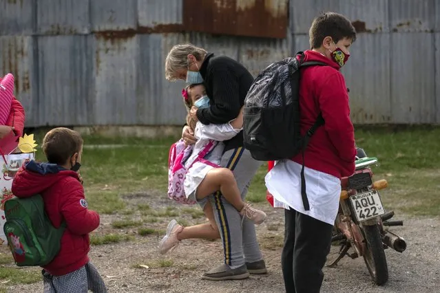 A student embraces a woman before entering school for the first time since it was closed due to the COVID-19 pandemic in Migues, Uruguay, Monday, May 3, 2021. Uruguay returned to face-to-face classes in some rural schools that have fewer than 20 students total and one teacher. (Photo by Matilde Campodonico/AP Photo)