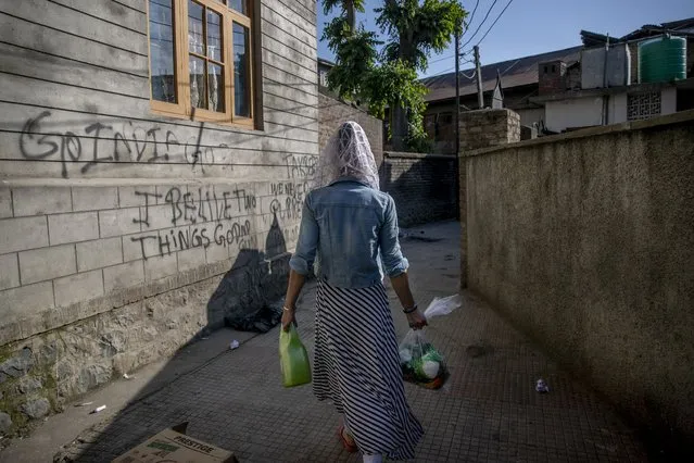 Sabu Sheikh, a transgender Kashmiri, walks homeward after collecting food handouts in Srinagar, Indian controlled Kashmir, Thursday, May 27, 2021. Kashmir's  transgender are often only able to find work as matchmakers or wedding entertainment. Prolonged coronavirus lockdowns, preceded by a strict security lockdown in the region in 2019 when India scrapped Kashmir's semi-autonomous status, left many in the transgender community with no work at all. (Photo by Dar Yasin/AP Photo)