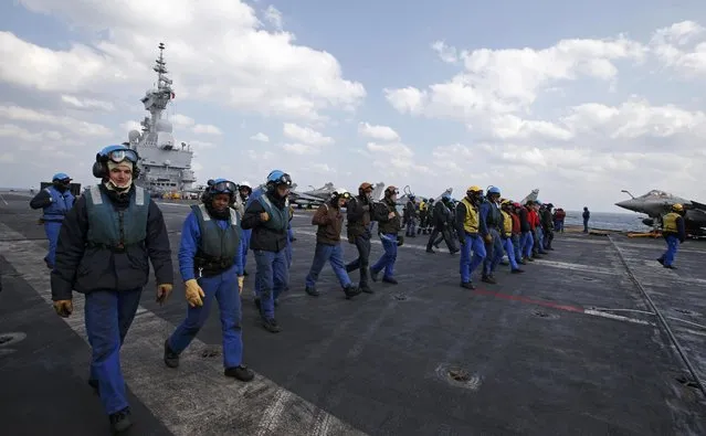 Crew members walk on the flight deck of France's Charles de Gaulle aircraft carrier to pick up any debris that might cause an accident during operations with jets in the Gulf, January 29, 2016. (Photo by Philippe Wojazer/Reuters)
