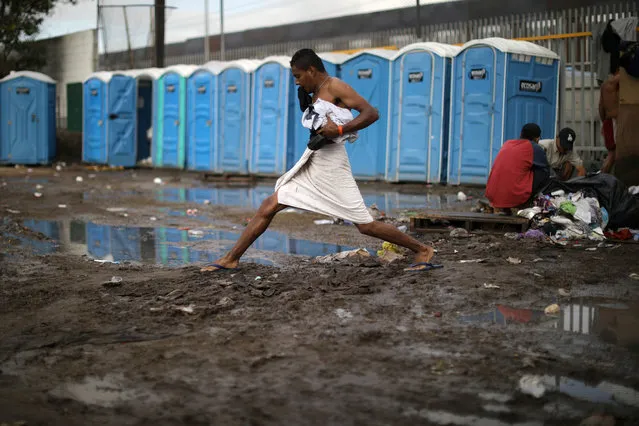 A migrant, part of a caravan of thousands from Central America trying to reach the United States, steps across mud after taking a shower at a temporary shelter in Tijuana, Mexico, Thursday, November 29, 2018. Aid workers and humanitarian organizations expressed concerns Thursday about the unsanitary conditions at the sports complex in Tijuana where more than 6,000 Central American migrants are packed into a space adequate for half that many people and where lice infestations and respiratory infections are rampant. (Photo by Lucy Nicholson/Reuters)