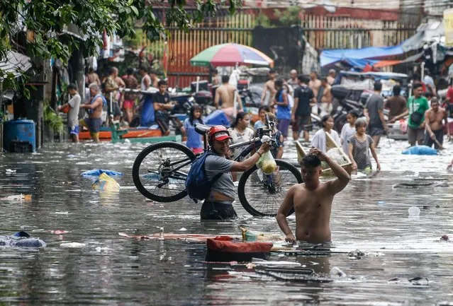 Residents wade through the floodwater as they move along a flooded road in Quezon City, Metro Manila, Philippines on August 31, 2023. Typhoon Saola, which has left the Philippine Area of Responsibility, and Tropical Storm Haikui off the coast of extreme northern provinces are enhancing a southwest monsoon bringing rains in the western Luzon region of the country, according to data from the Philippine Atmospheric Geophysical and Astronomical Services Administration (PAGASA). Figures from the National Disaster Risk Reduction and Management Council (NDRRMC) show that over 305,000 individuals were affected by the passing of Typhoon Saola. (Photo by Rolex Dela Pena/EPA/EFE)