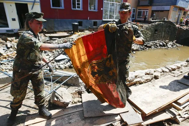 German Bundeswehr soldiers rescue a German national flag as they help to clean up following heavy rainfalls, in Bad Muenstereifel, North Rhine-Westphalia state, Germany, July 21, 2021. (Photo by Thilo Schmuelgen/Reuters)