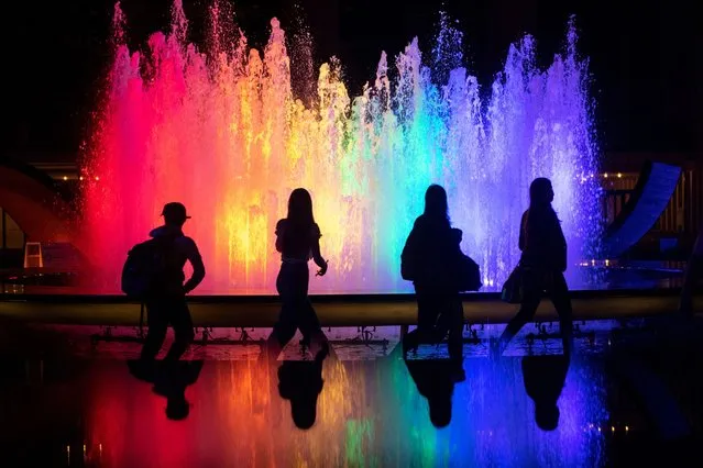 A silhouette of people walk past the fountain at Lincoln Center for the Performing Arts lit up in pride colors on June 02, 2021 in New York City. On May 19, 2021 New York Governor Andrew Cuomo lifted all coronavirus pandemic restrictions paving the way for most Pride month events to resume normally. New York City Pride weekend will be June 25th-27th. (Photo by Alexi Rosenfeld/Getty Images)