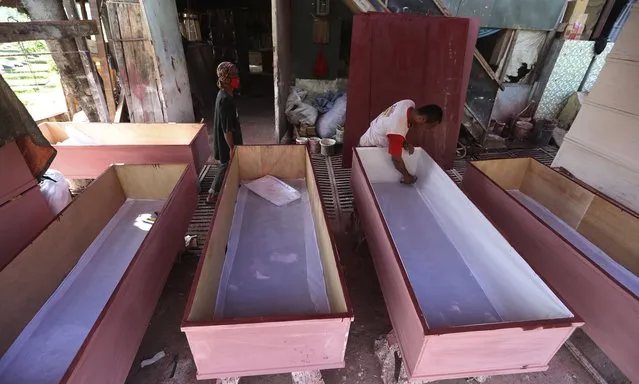 Workers make coffins to be used for victims of the coronavirus in Jakarta, Indonesia, Tuesday, July 27, 2021. Indonesia has been showing sharp increases since late June. (Photo by Achmad Ibrahim/AP Photo)