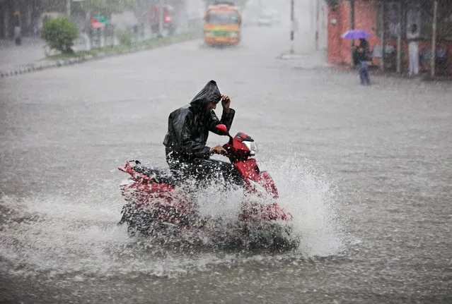 An Indian man rides a bike on a waterlogged road as it rains in Jammu, India, Friday, August 8, 2014. India's monsoon season, which runs from June to September, bring rains that are vital to agriculture but also cause floods and landslides. (Photo by Channi Anand/AP Photo)
