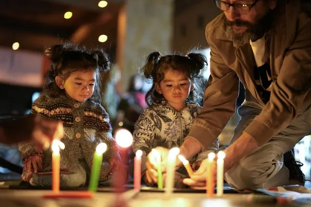 A family lights candles during the day of solidarity with the Palestinian people, in Bogota, Colombia, Wednesday, November 29, 2023. (Photo by Fernando Vergara/AP Photo)