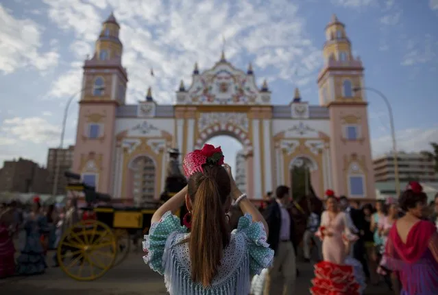 A girl wearing a sevillana dress takes pictures during the traditional Feria de Abril (April fair) in the Andalusian capital of Seville, southern Spain, April 21, 2015. (Photo by Marcelo del Pozo/Reuters)