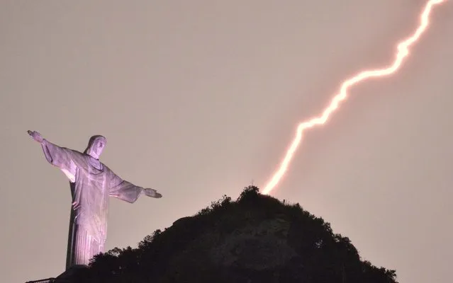 Lightning flashes over the Christ the Redeemer statue on top of Corcovado Hill in Rio de Janeiro on January 16, 2014. (Photo by Marcello Dias/Futura Press)