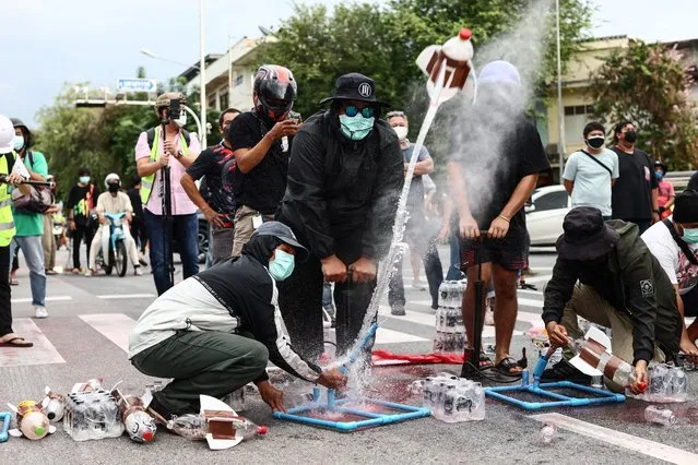 Anti-government protesters use water pressure to launch homemade projectiles during a demonstration in Bangkok on September 27, 2021, as activists call for the resignation of Thailand's Prime Minister Prayut Chan-O-Cha over the government's handling of the Covid-19 coronavirus crisis. (Photo by Jack Taylor/AFP Photo)