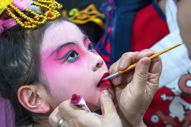 A teacher of Peking Opera is putting makeup on a child during a Peking Opera performance in Hai'an, China, on January 30, 2024. (Photo by Costfoto/NurPhoto/Rex Features/Shutterstock)
