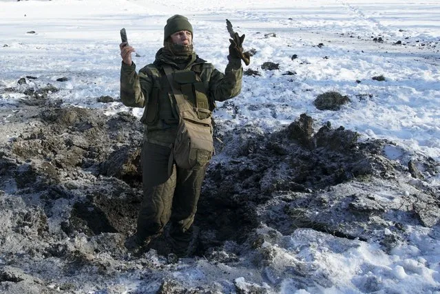 A Ukrainian soldier shows pieces of shrapnel in a crater left by an explosion in Avdiivka, Ukraine, Tuesday, January 31, 2017. Fighting between government troops and Russia-backed separatist rebels in eastern Ukraine escalated on Tuesday, killing at least eight people late Monday and early Tuesday, injuring dozens and briefly trapping more than 200 coal miners underground, the warring sides reported. (Photo by Inna Varenytsia/AP Photo)