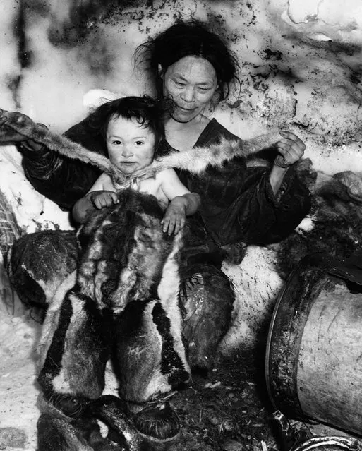 An Inuit mother dresses her young child in a fur snowsuit. (Photo by Hulton-Deutsch Collection/Corbis via Getty Images)