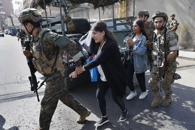 Lebanese army special forces soldiers assist teachers as they flee their school after deadly clashes erupted nearby along a former 1975-90 civil war front-line between Muslim Shiite and Christian areas at Ain el-Remaneh neighborhood, in Beirut, Lebanon, Thursday, October 14, 2021. (Photo by Hussein Malla/AP Photo)