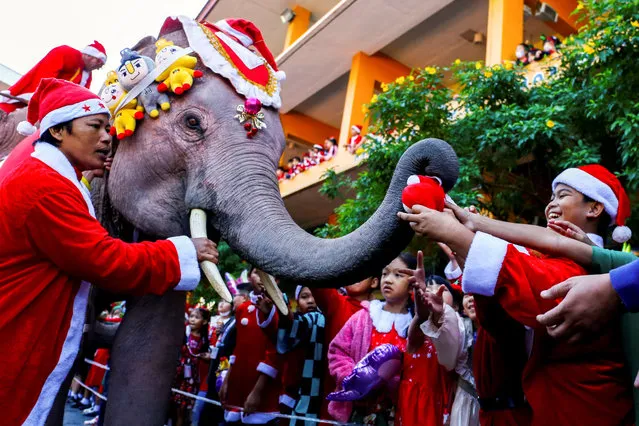 Students wait for gifts from an elephant dressed in a Santa Claus costume ahead of Christmas celebrations at a school, in Ayutthaya, Thailand on December 22, 2023. (Photo by Artorn Pookasook/Reuters)