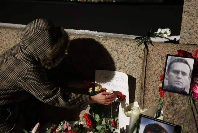 Flowers and portraits of Russian opposition leader Alexei Navalny are placed at the monument to the victims of political repression in Saint Petersburg, Russia, on February 16, 2024. The placard reads: “Love is stronger than fear”. (Photo by Reuters/Stringer)