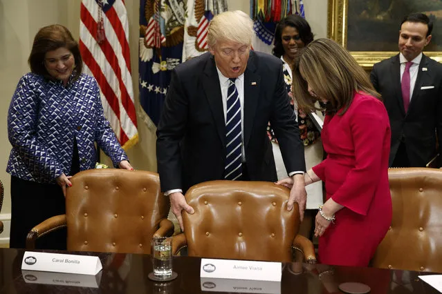 Carol Bonilla, left, watches as President Donald Trump helps Aimee Viana with her chair during a meeting with parents and teachers, Tuesday, February 14, 2017, in the Roosevelt Room of the White House in Washington. (Photo by Evan Vucci/AP Photo)