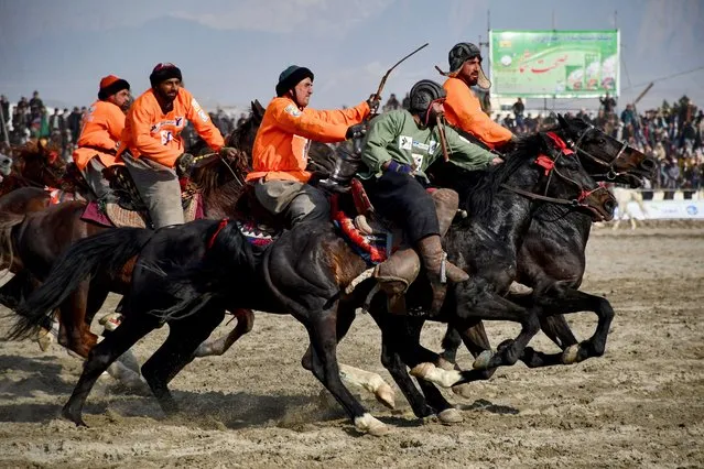 This photograph taken on March 8, 2024 shows Afghan riders of the Yama Petroleum (orange) and Baghlan teams competing at the Buzkashi league tournament final in Mazar-i- Sharif. Played for centuries in Afghanistan's northern steppes, the national sport at the heart of Afghan identity has evolved from a rough, rural pastime to a professionalised phenomenon flush with cash. Traditionally, buzkashi is played with the headless body of a goat. More often a 30-kilogramme (66-pound) leather sack stands in for the carcass that riders try to pull from a fray of horses and drop in a “circle of justice” traced on the ground. (Photo by Atif Aryan/AFP Photo)