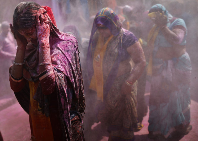 Women cover their faces as men throw coloured powder at them during “Lathmar Holi” at the village of Barsana in the northern Indian state of Uttar Pradesh March 9, 2014. (Photo by Anindito Mukherjee/Reuters)