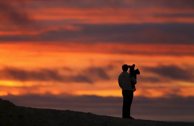 A father and his son watch the sun set in Encinitas, California January 19, 2016. (Photo by Mike Blake/Reuters)